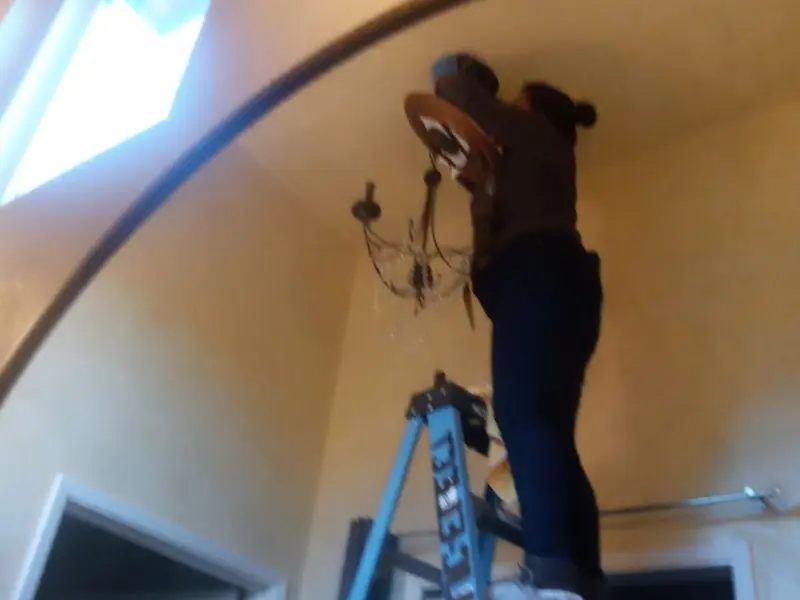 Electrician installing a chandelier in a Castroville residence